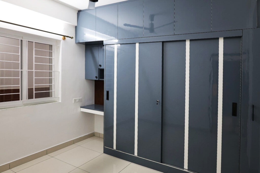 bedroom with glossy blue sliding wardrobe and built-in study nook.