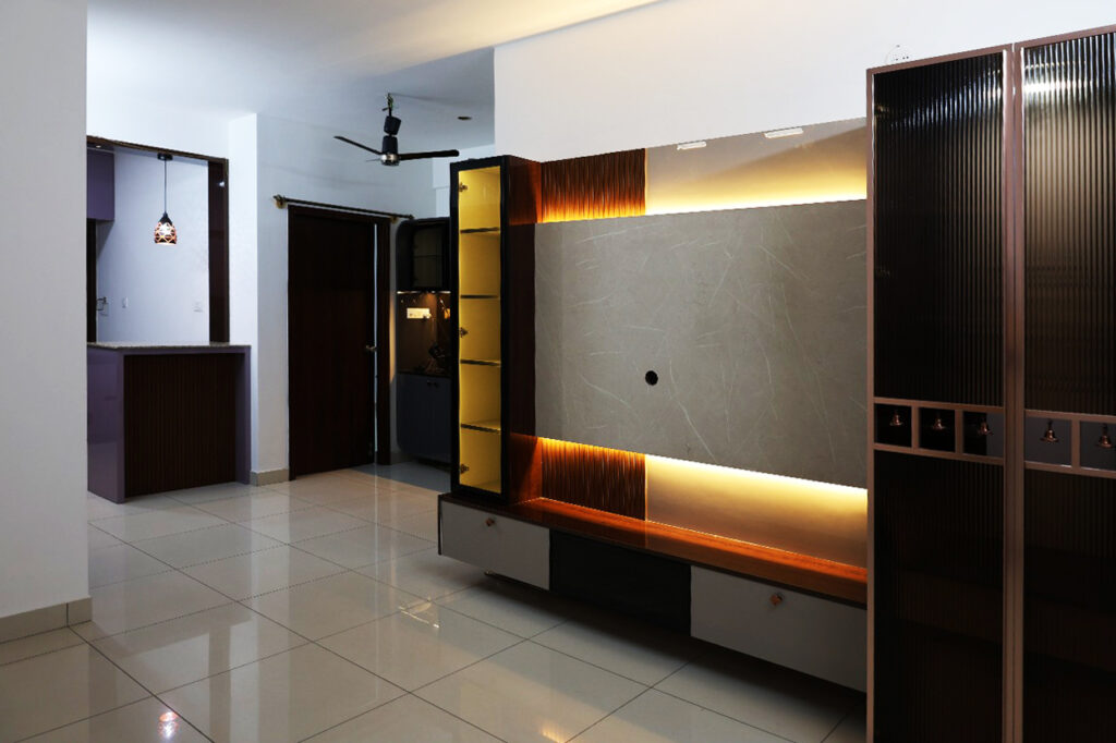 Modern living room with a sleek TV unit, warm LED lighting, and tiled flooring.